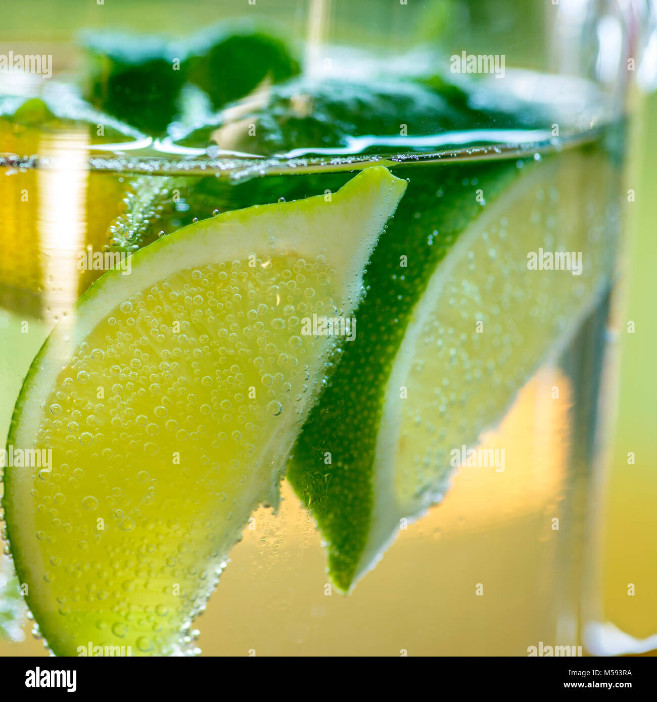 Fresh lemonade with slices of limes in a glass pot Stock Photo