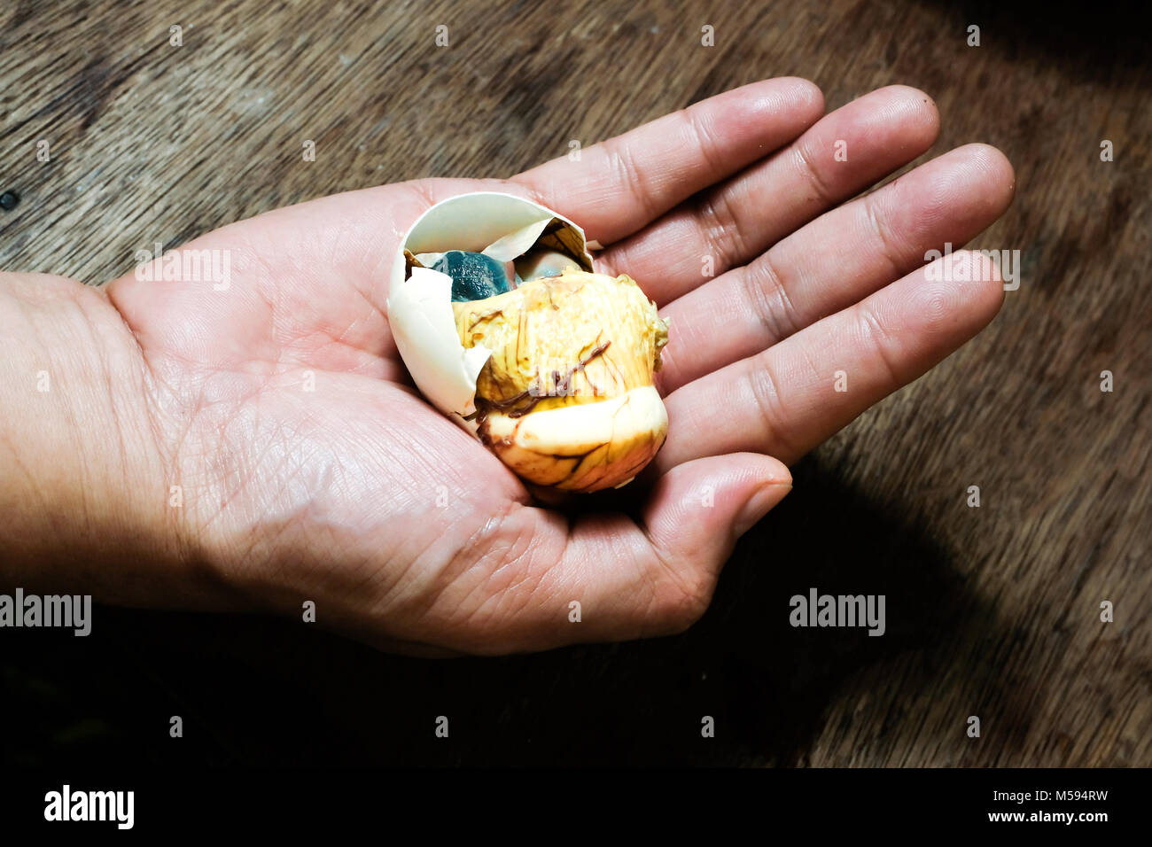 A partially opened balut, cooked fertilized duck egg, pictured on a hand in Metro Manila, The Philippines Stock Photo