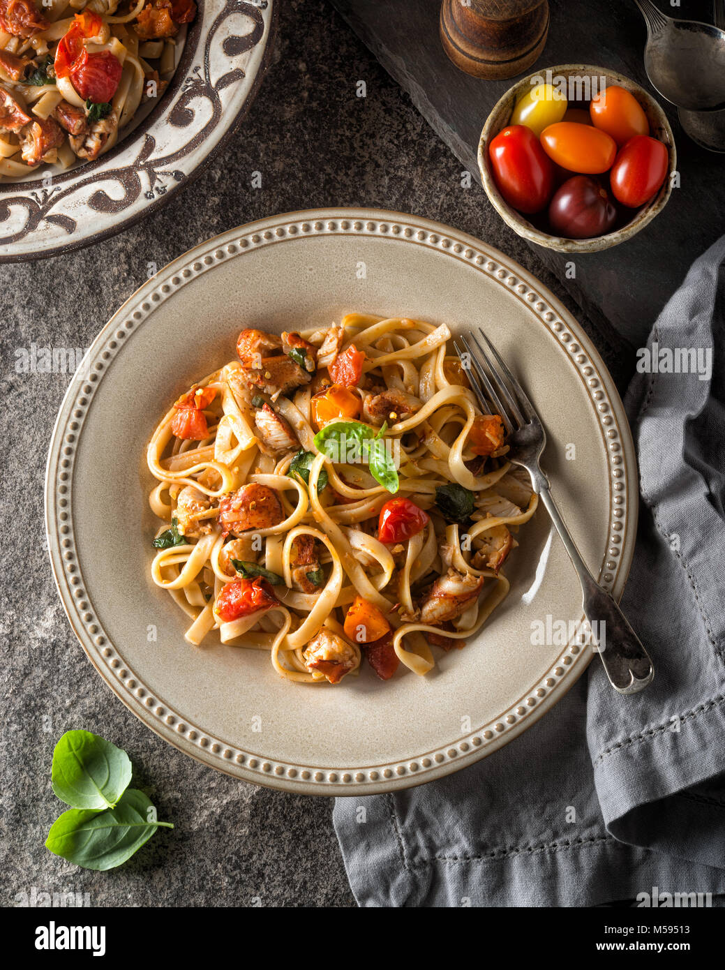 A plate of delicious homemade lobster fettuccine with heirloom tomatoes and basil. Stock Photo
