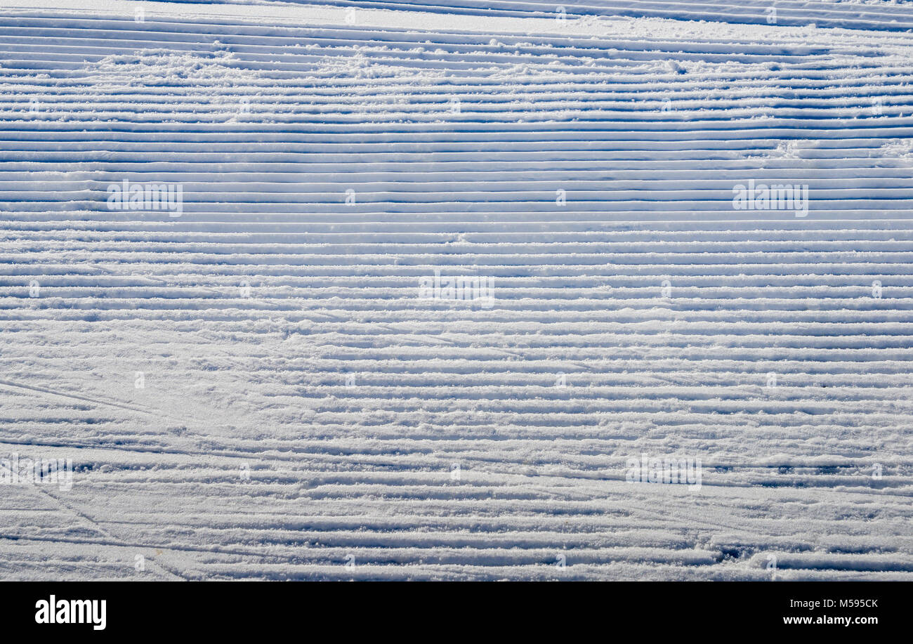 Newly groomed snow on ski slope on a sunny winter day Stock Photo