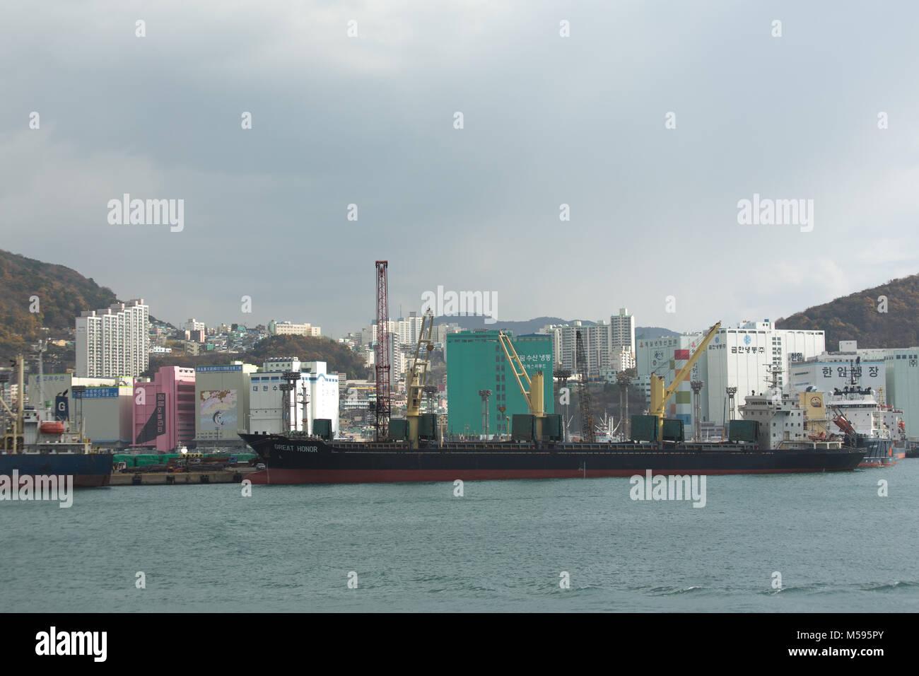 Busan, South Korea - December 3rd, 2015: Busan, view on port with the ship Great Honor and city. Stock Photo