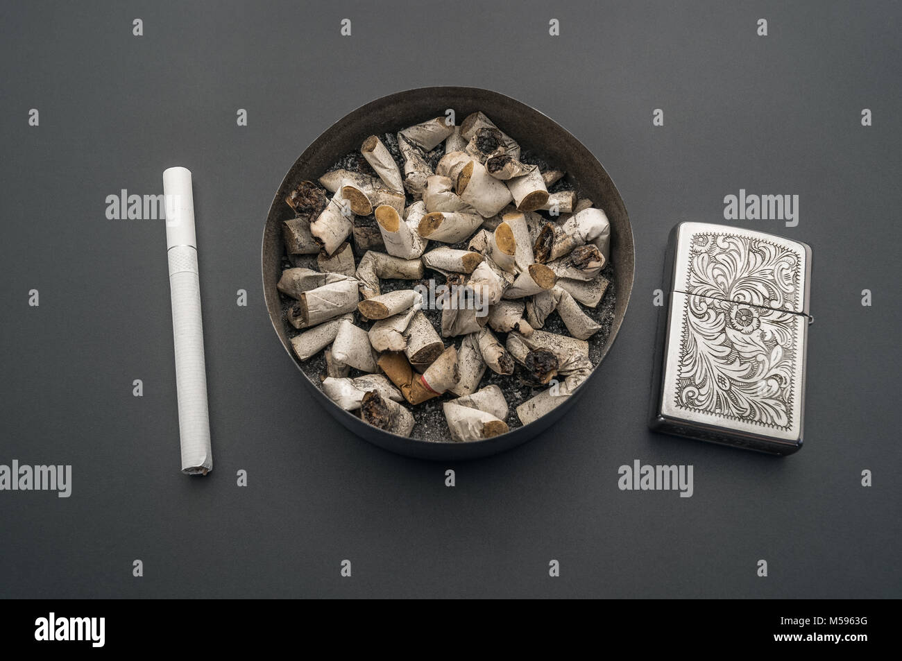 Ashtray with cigarette butts against the background of a gray table. A