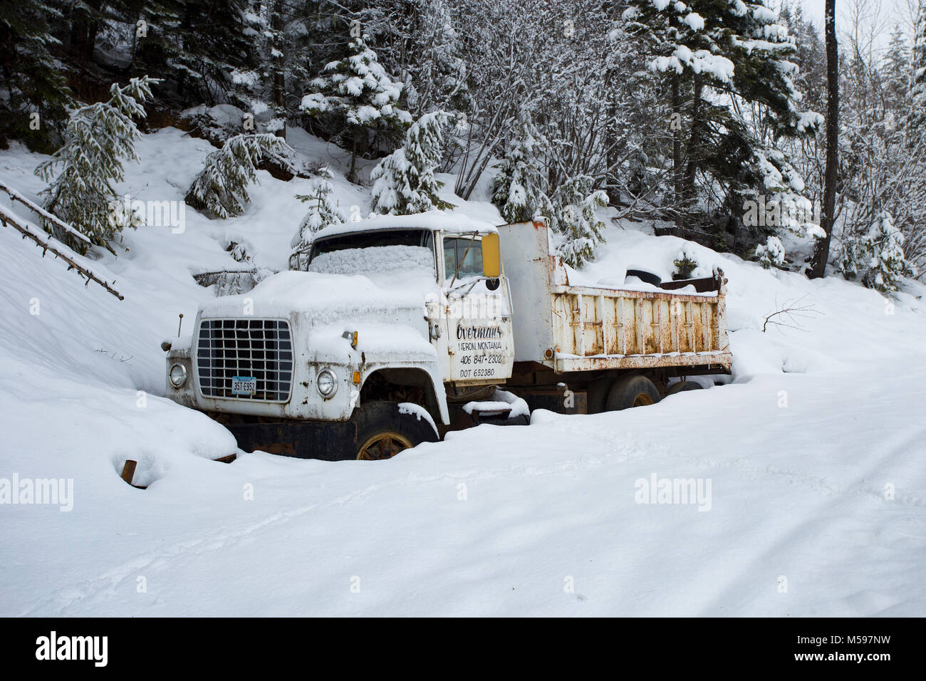 A snow-covered 1980 Ford L9000 dump truck along the side of the road, at Eagle View, in the Cabinet Mountains, of Sanders County, Montana Stock Photo