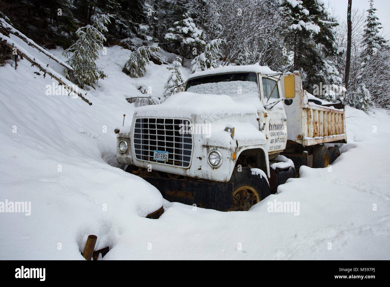 A snow-covered 1980 Ford L9000 dump truck along the side of the road, at Eagle View, in the Cabinet Mountains, of Sanders County, Montana Stock Photo