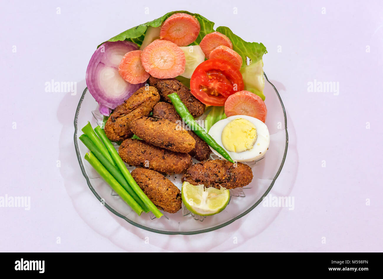 Crispy deep fried fish finger Indian starter dish garnished with beans with slices of egg, carrot tomato and onion Stock Photo