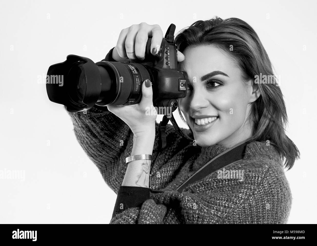 Pretty Young smiling girl taking a photo with a professional DSLR