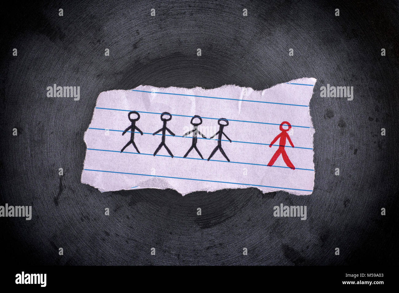 Piece of paper with drawn people and the red one is the odd one out. Concept Image. Close up. Stock Photo