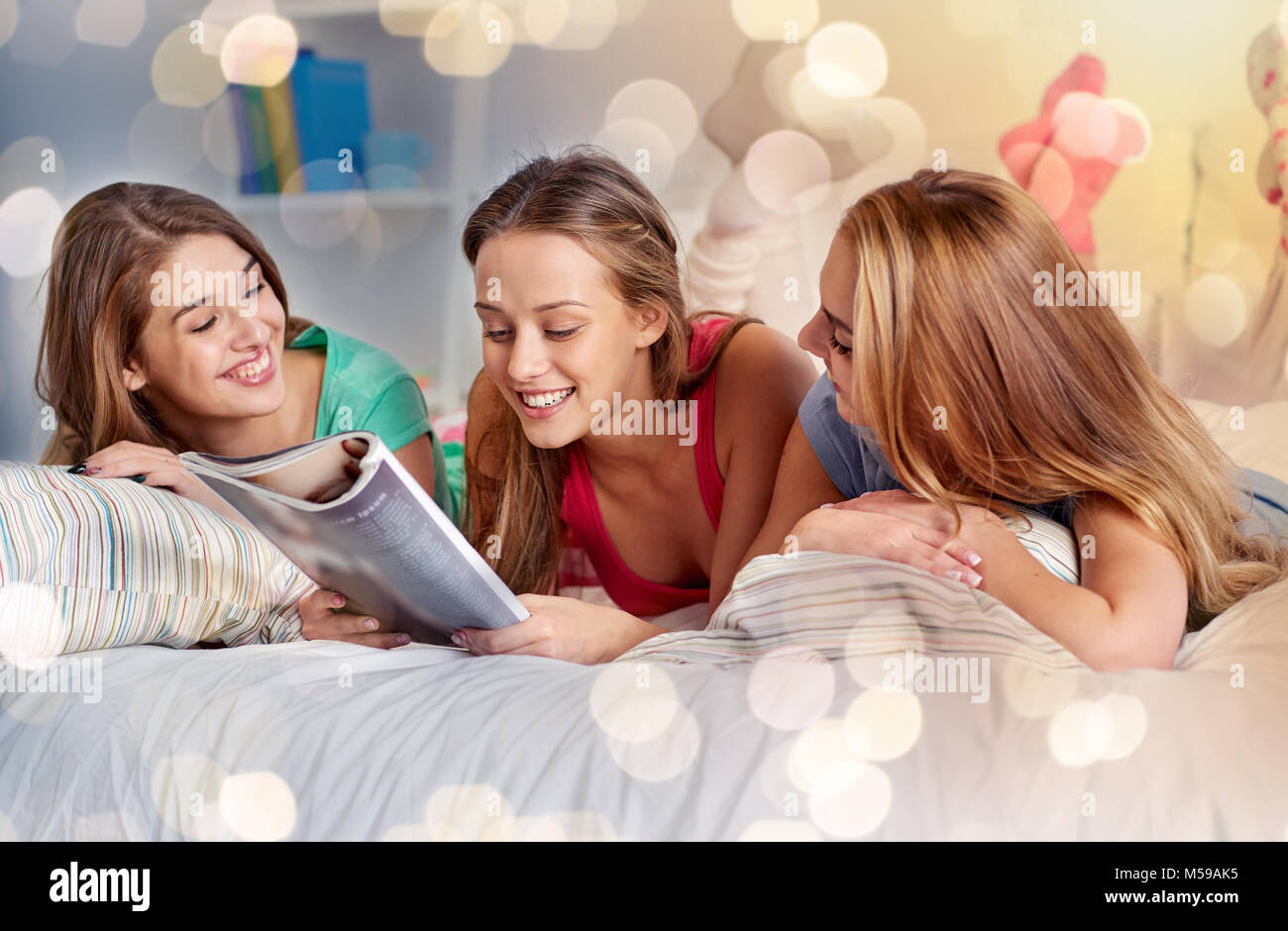 friends or teen girls reading magazine at home Stock Photo