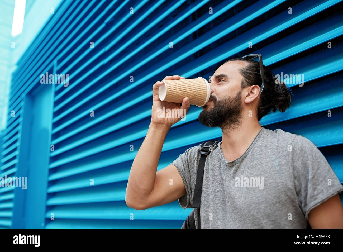 man drinking coffee from paper cup over wall Stock Photo - Alamy