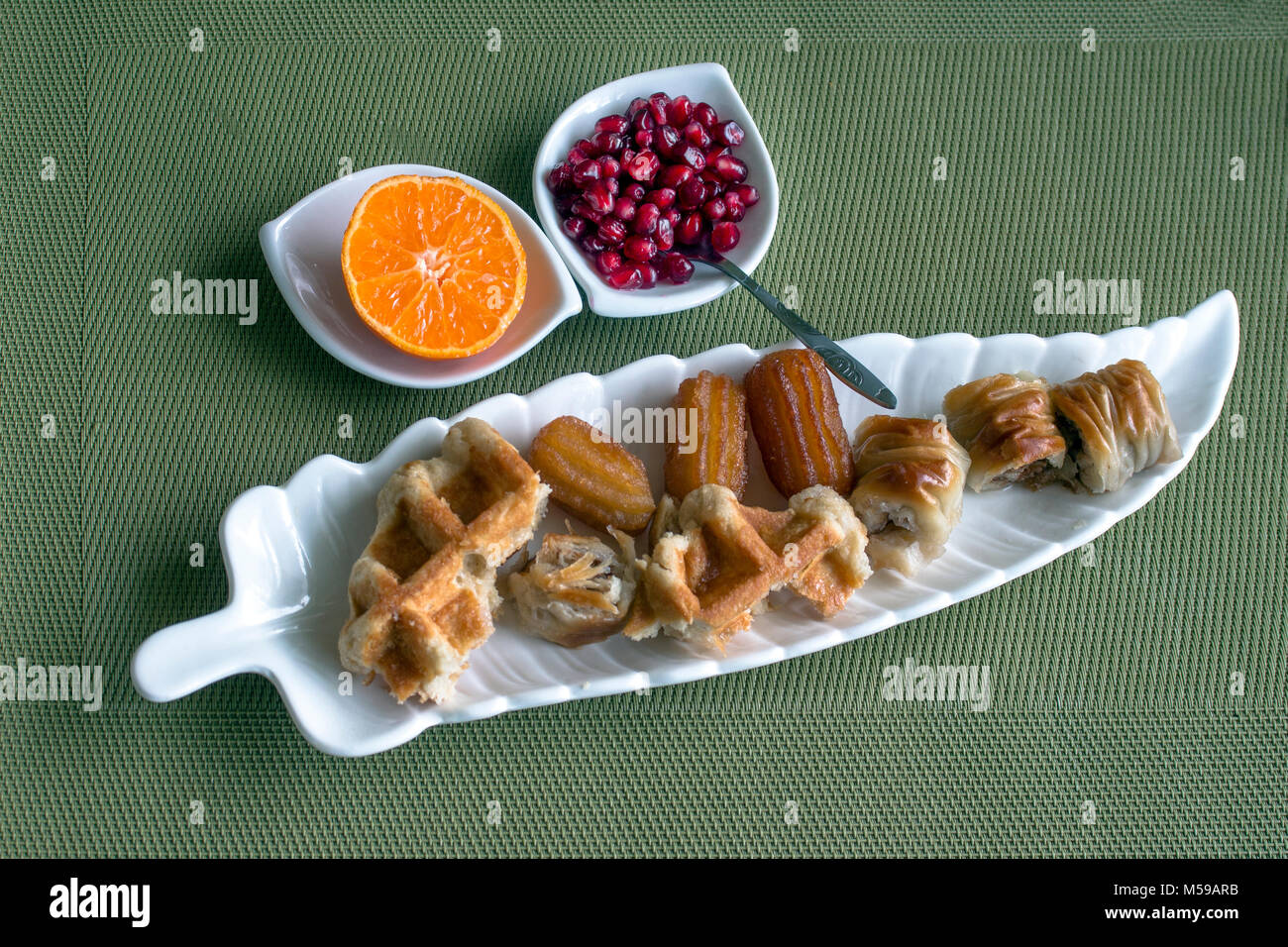 Small syrupy pastries and fruits - mandarin and pomegranate. Stock Photo