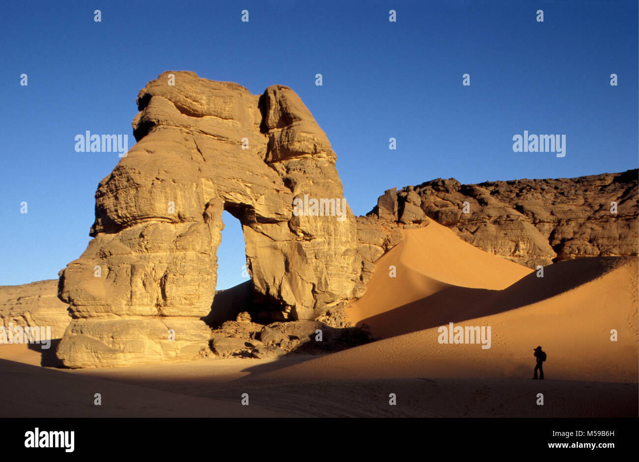 Libya. Near Ghat. Sahara desert. Akakus (Acacus) National Park. Natural arch called Fezzenger. Tourist, woman. Stock Photo