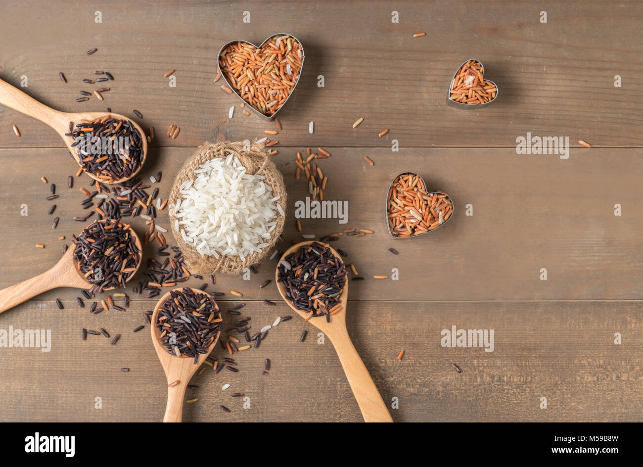 Row of white jasmine rice with various rice:  Rice berry, brown and thai red mixed rice on brown wooden background, organic rice and healthy food. Stock Photo