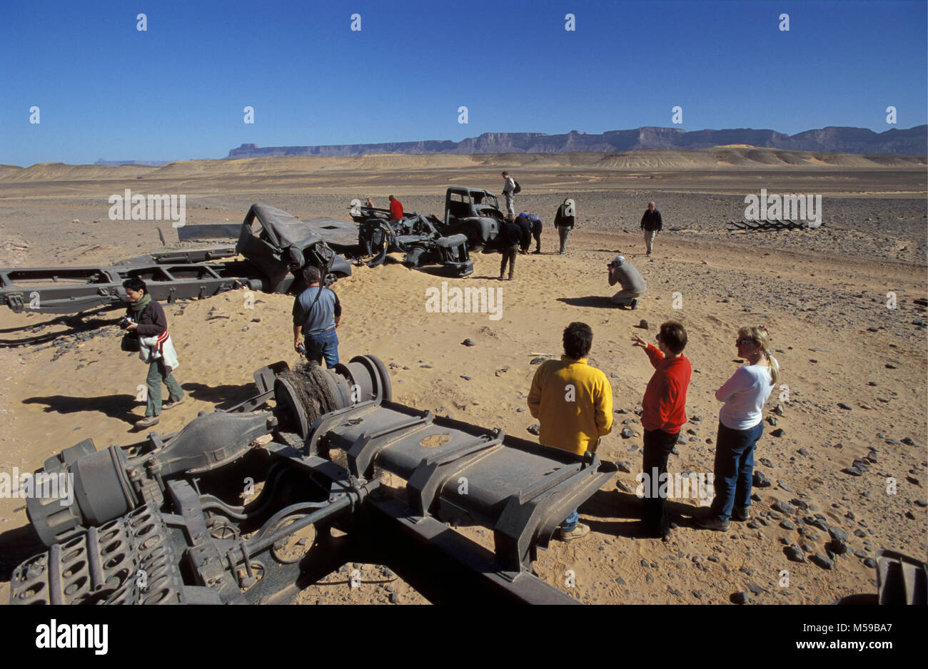 Libya. Ghat Sahara desert. Tourists survey wrecked Italian army trucks from a Second World War battle with the French in the Sahara Desert. Stock Photo
