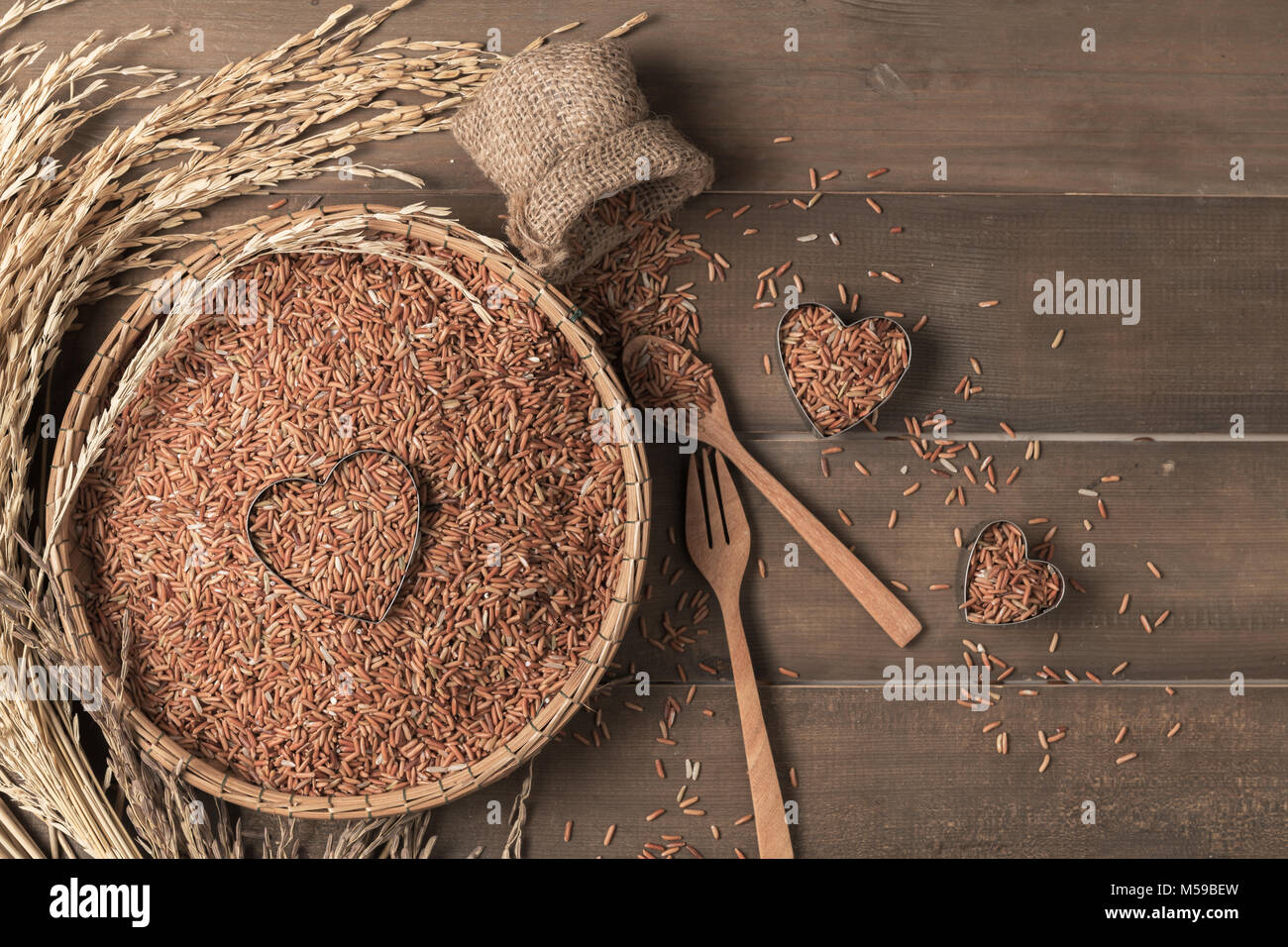 Thai brown jasmine rice or Rice berry in bamboo basket and on wood background, love organic rice and healthy food Stock Photo