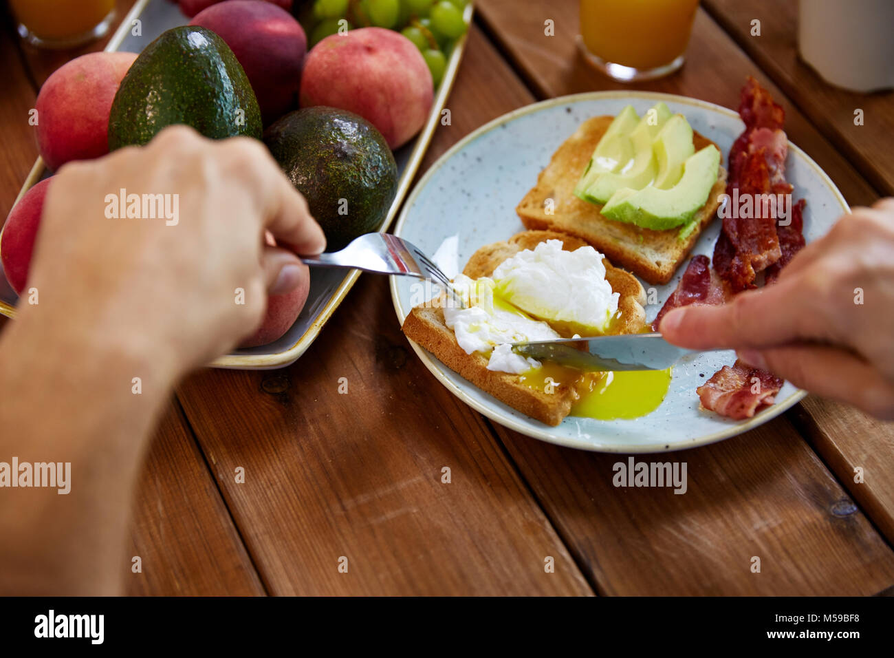 man eating toast with pouched egg and bacon Stock Photo