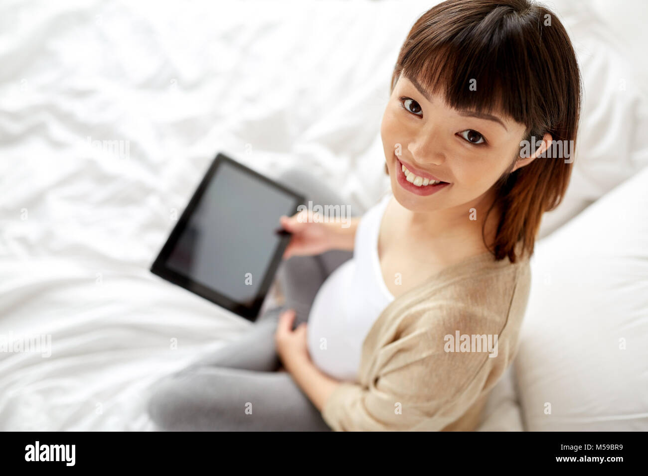 happy pregnant asian woman with tablet pc at home Stock Photo - Alamy