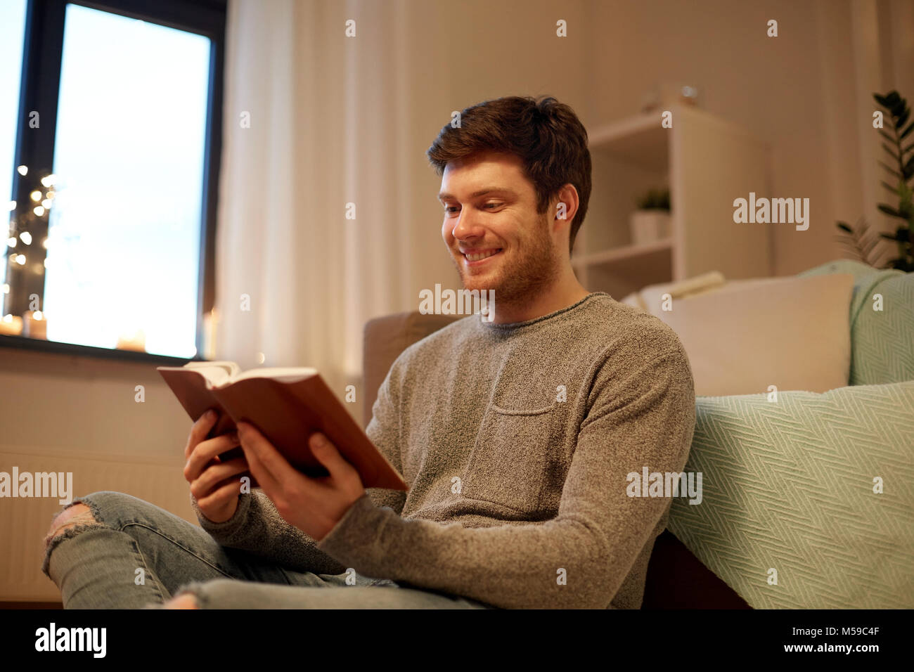 happy young man reading book at home Stock Photo