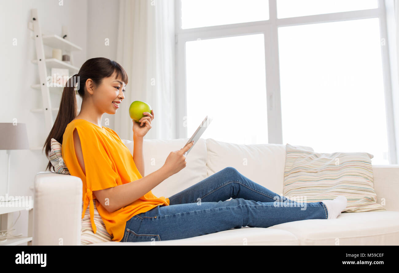 happy asian woman with tablet pc and apple at home Stock Photo - Alamy