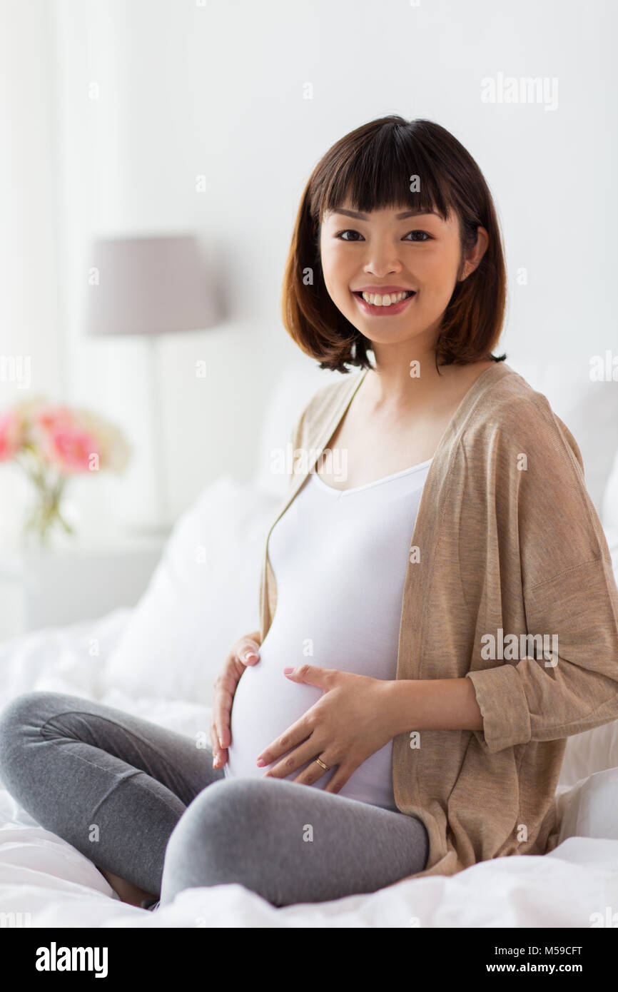 https://c8.alamy.com/comp/M59CFT/happy-pregnant-asian-woman-sitting-in-bed-at-home-M59CFT.jpg