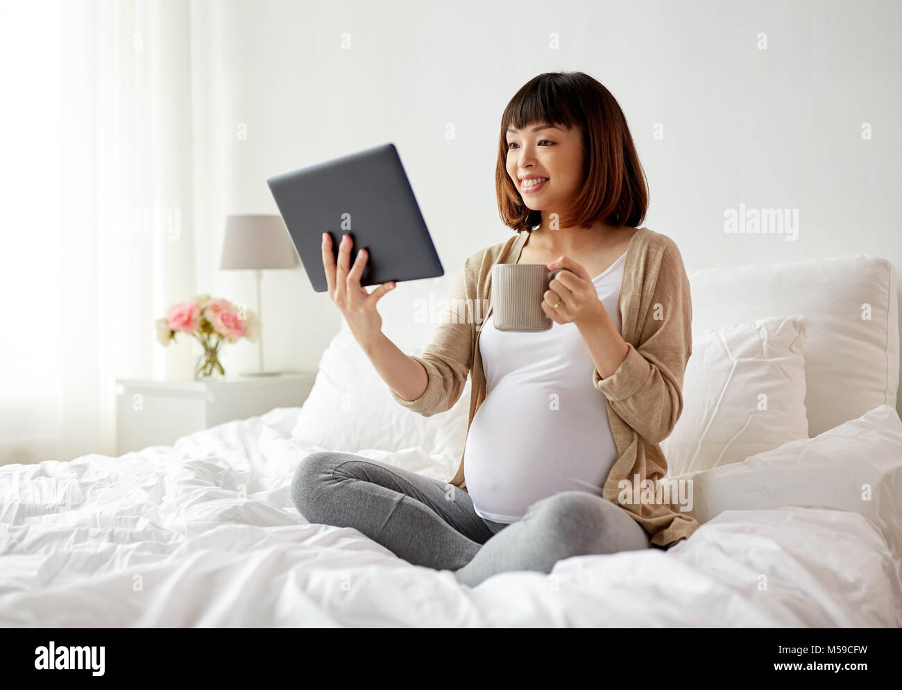 happy pregnant asian woman with tablet pc at home Stock Photo - Alamy