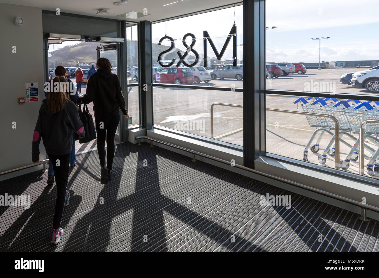 People walking exiting a Marks and Spencer store into a car park Stock
