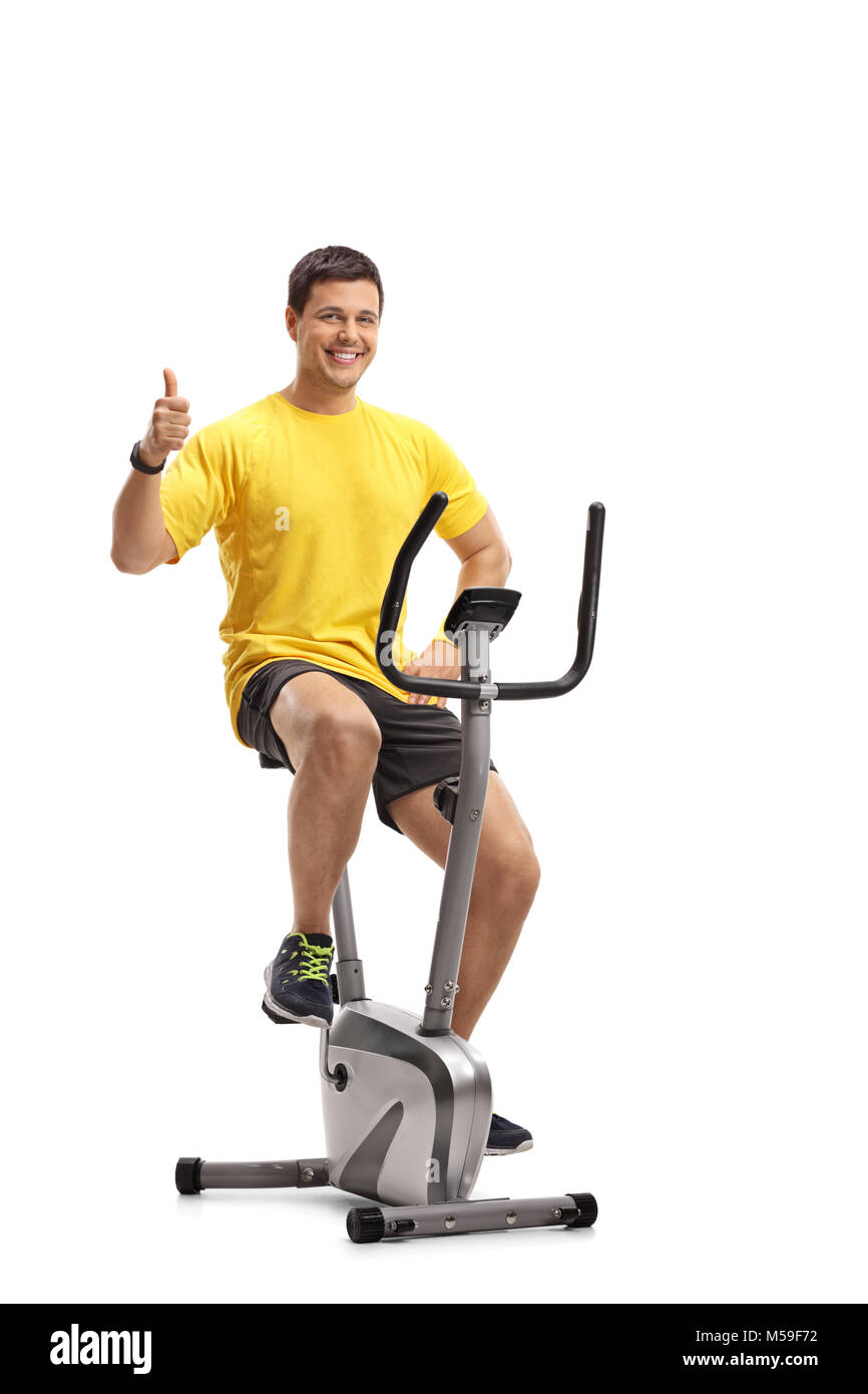 Young man exercising on a cross-trainer machine and making a thumb up gesture isolated on white background Stock Photo
