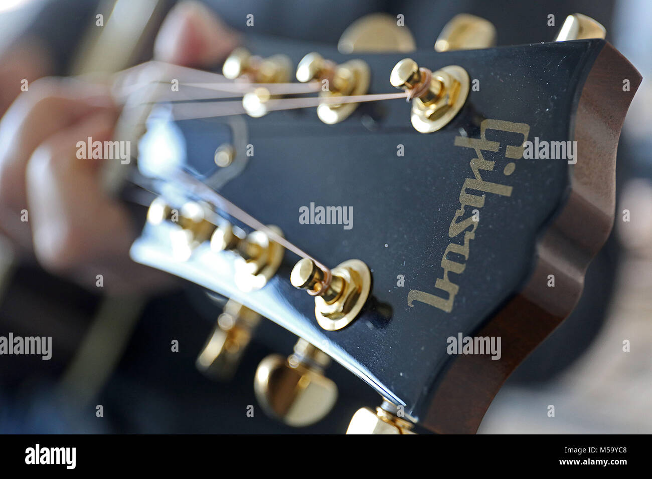 21 February 2018, Germany, Cologne: The logo reads 'Gibson' on the  headstock of a Gibson acoustic guitar. The established guitar manufacturer  from Nashville has to face an existential struggle: According to a '