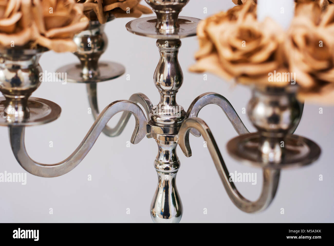 close up of a silver candelabrum with blurred golden roses Stock Photo