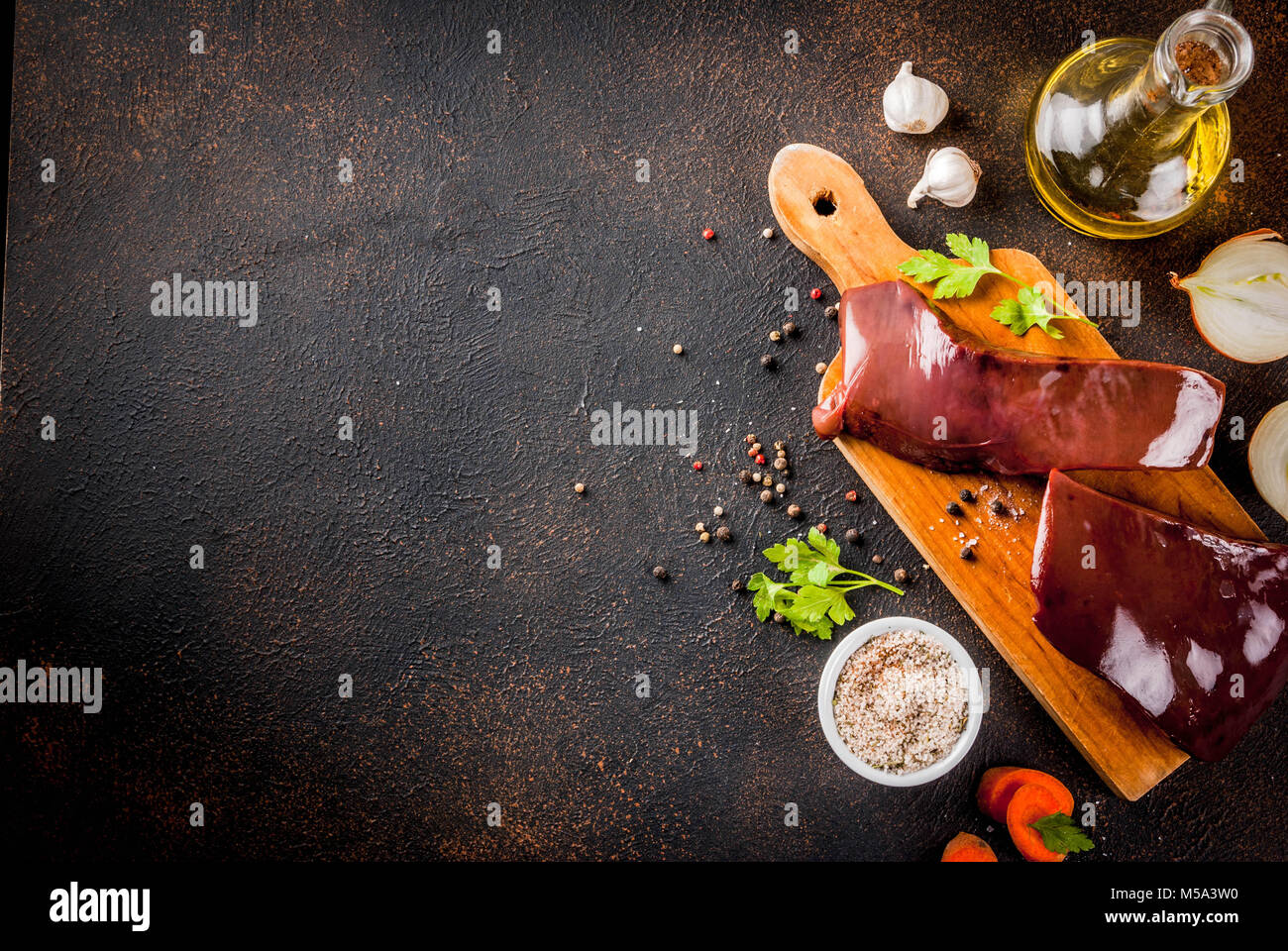 Raw beef liver with spices, herbs and vegetables, dark rusty table copy ...