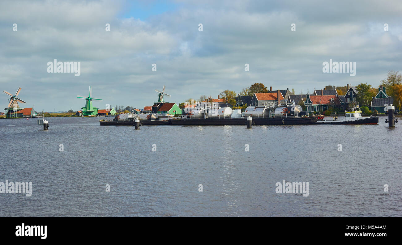 Tug boat pulling an industrial barge on the Zaan River, Zaanse Schans a village near Zaandijk in the municipality of Zaanstad, Netherlands Stock Photo