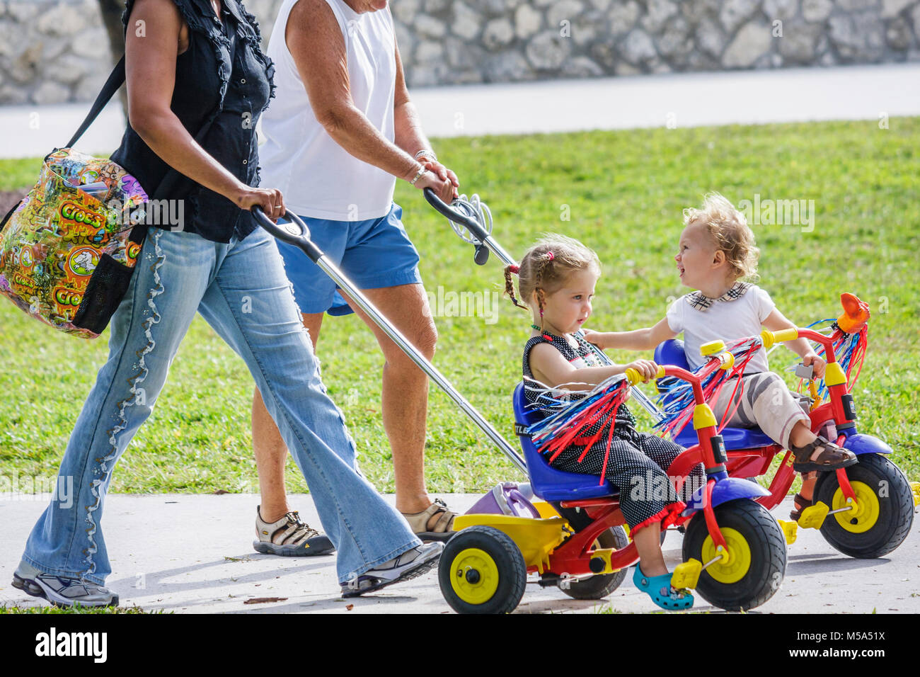 Miami Beach Florida,Ocean Drive,Lummus Park,toddlers,tricycles,pushed,Black nanny,grandmother,child care,baby babies child children,sit,outdoor,FL0803 Stock Photo