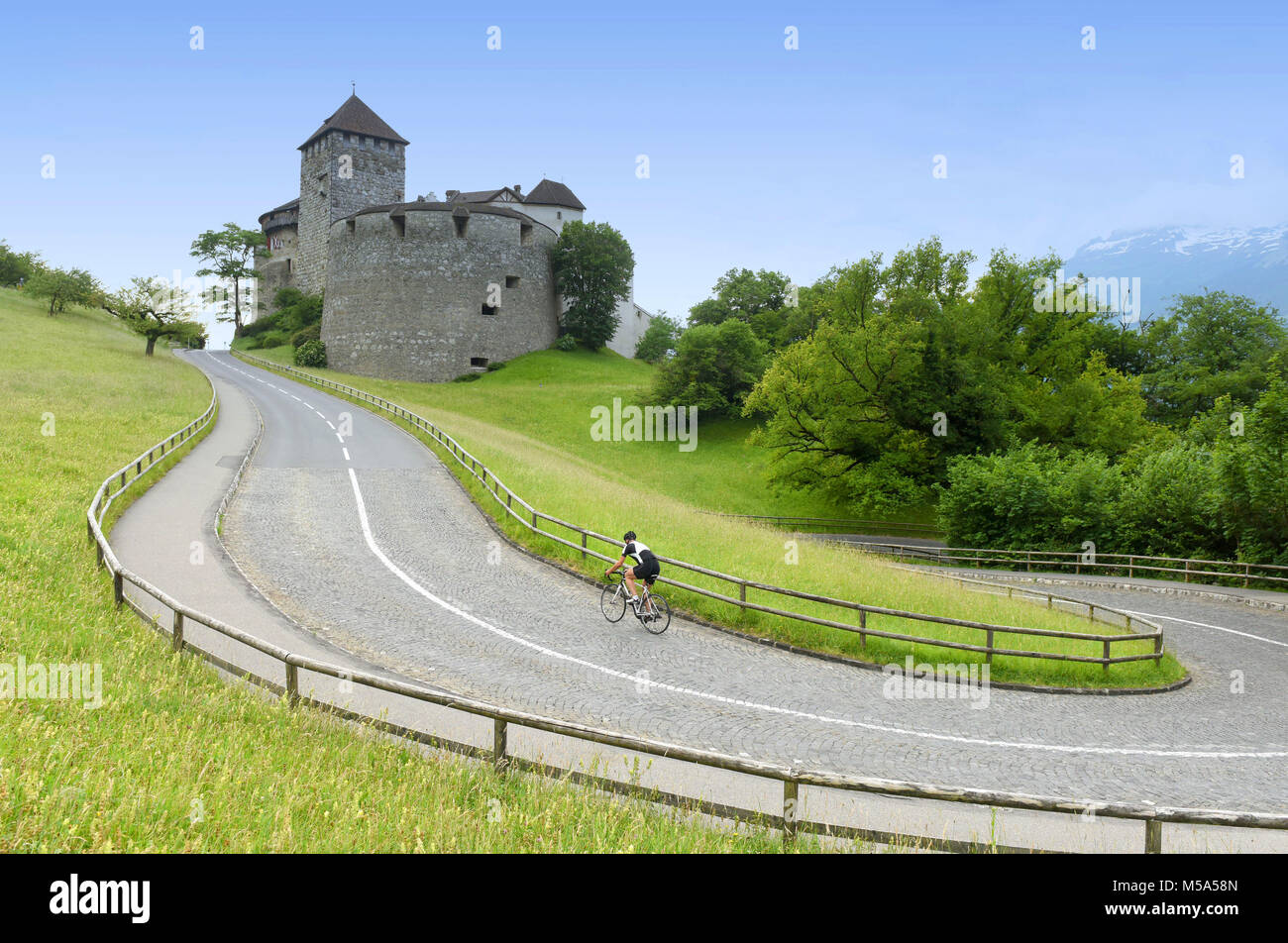 A bicyclist near Castle in Vaduz, Liechtenstein. This castle is the palace and official residence of the Prince of Liechtenstein Stock Photo