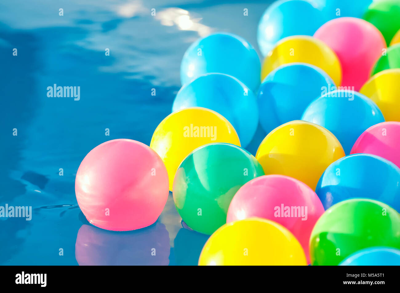 Multicolored plastic balls float in the children's pool Stock Photo