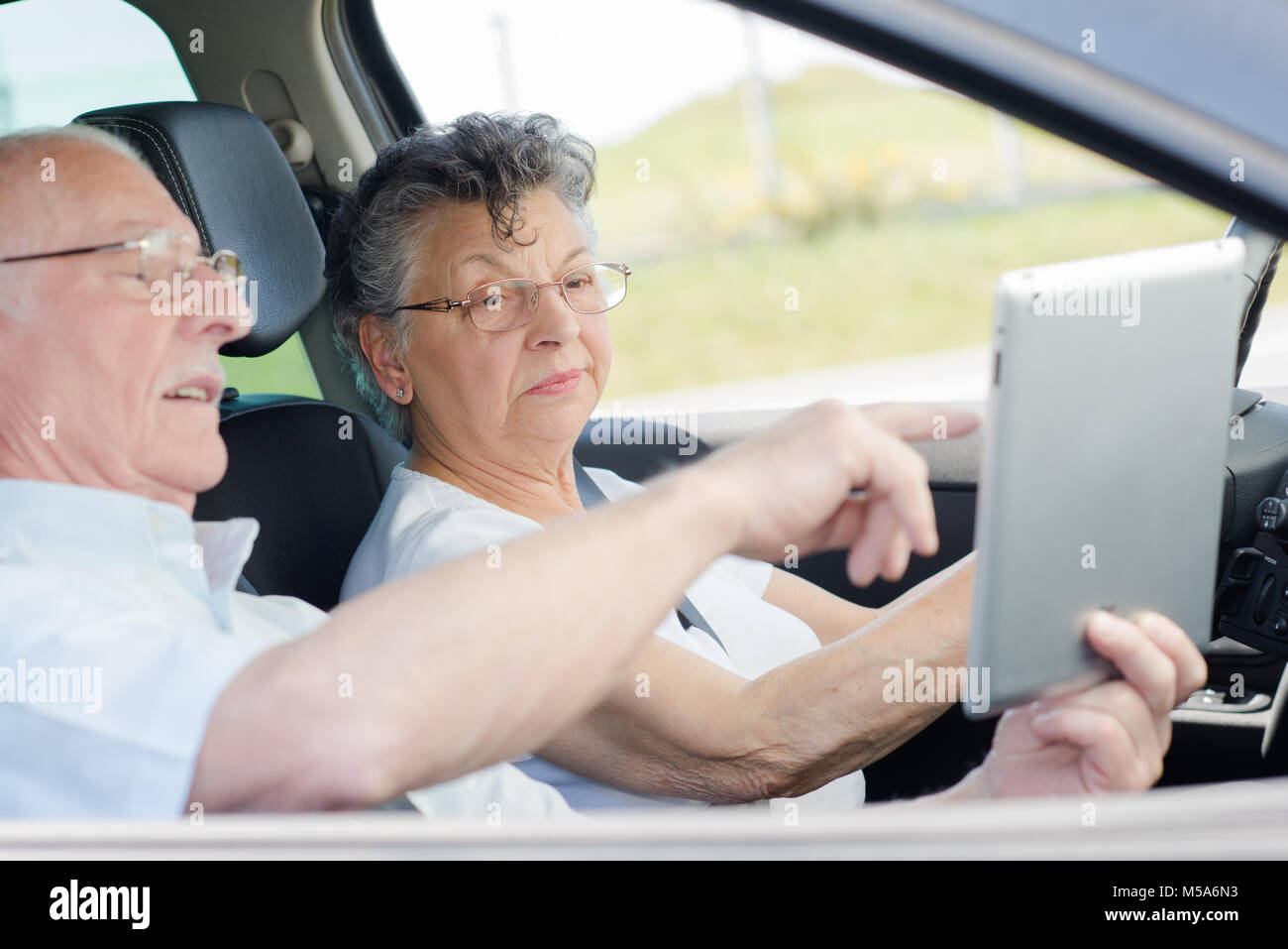 Senior couple looking at tablet in vehicle Stock Photo