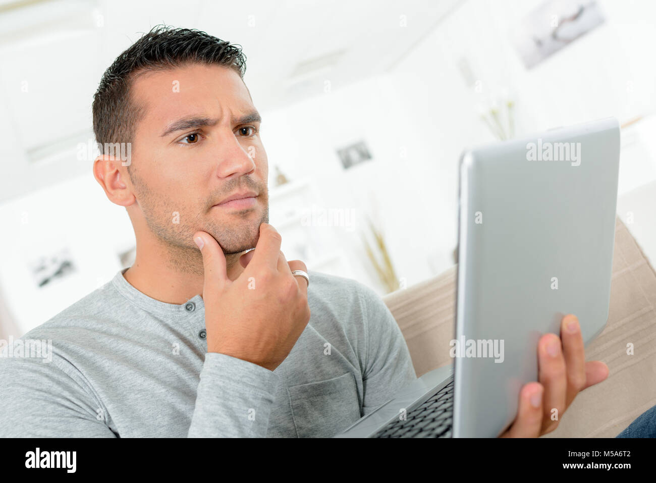 portrait of thinking man using laptop computer at home Stock Photo - Alamy