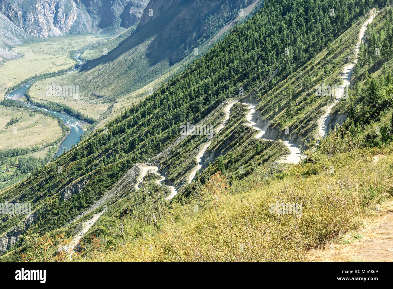 Scenic top view on the steep winding dirt road through the pass, part of the mountain serpentine, passing the slope of the mountain Stock Photo