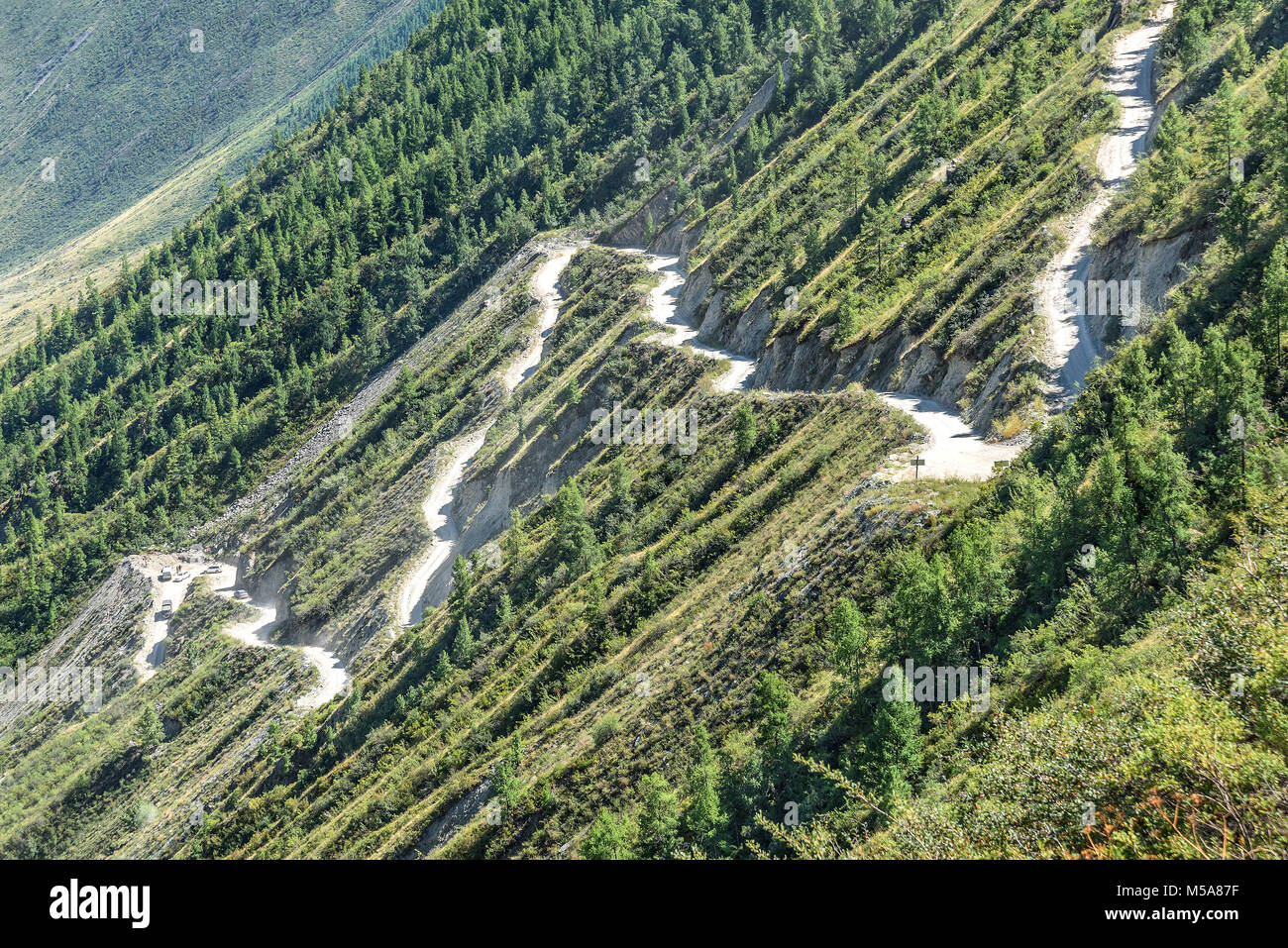 Scenic top view on the steep winding dirt road through the pass, part of the mountain serpentine, passing the slope of the mountain Stock Photo