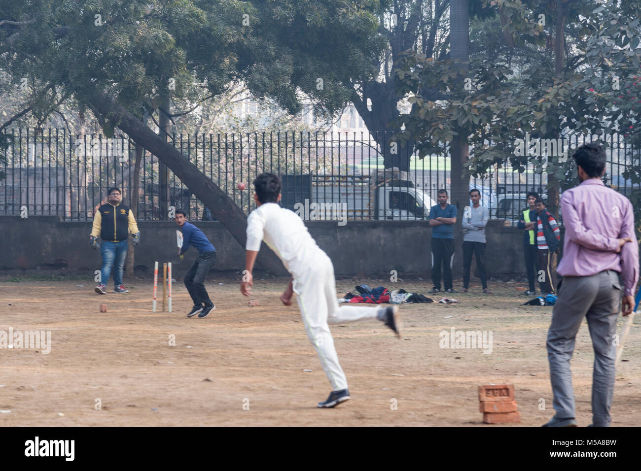 Young boys playing cricket at an outdoor location in New Delhi, India