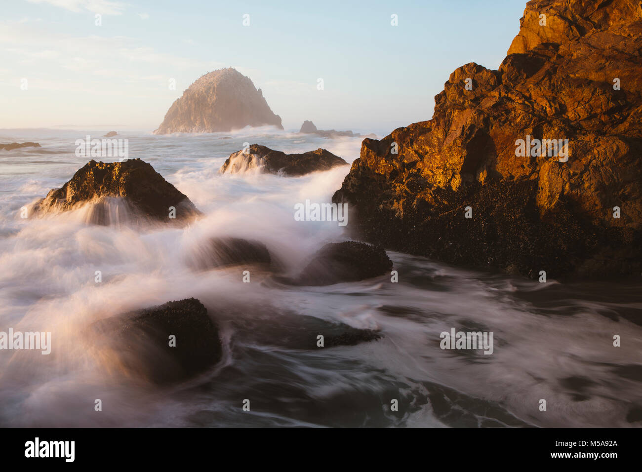 Seascape with breaking waves over rocks at dusk. Stock Photo