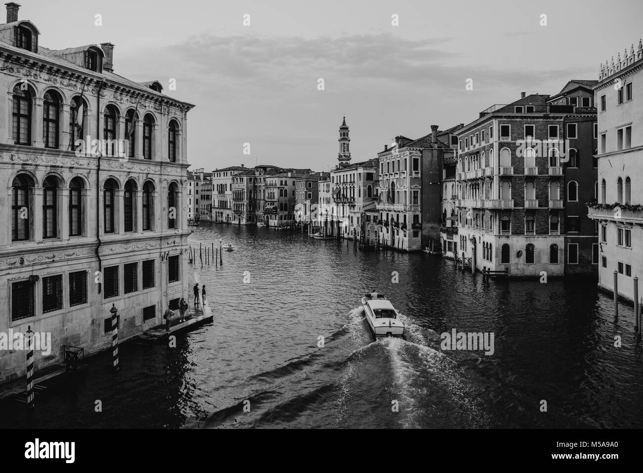 Black and white view of a speed boat navigating through Grand Canal and the buildings from Rialto bridge in Venice, Italy. Stock Photo