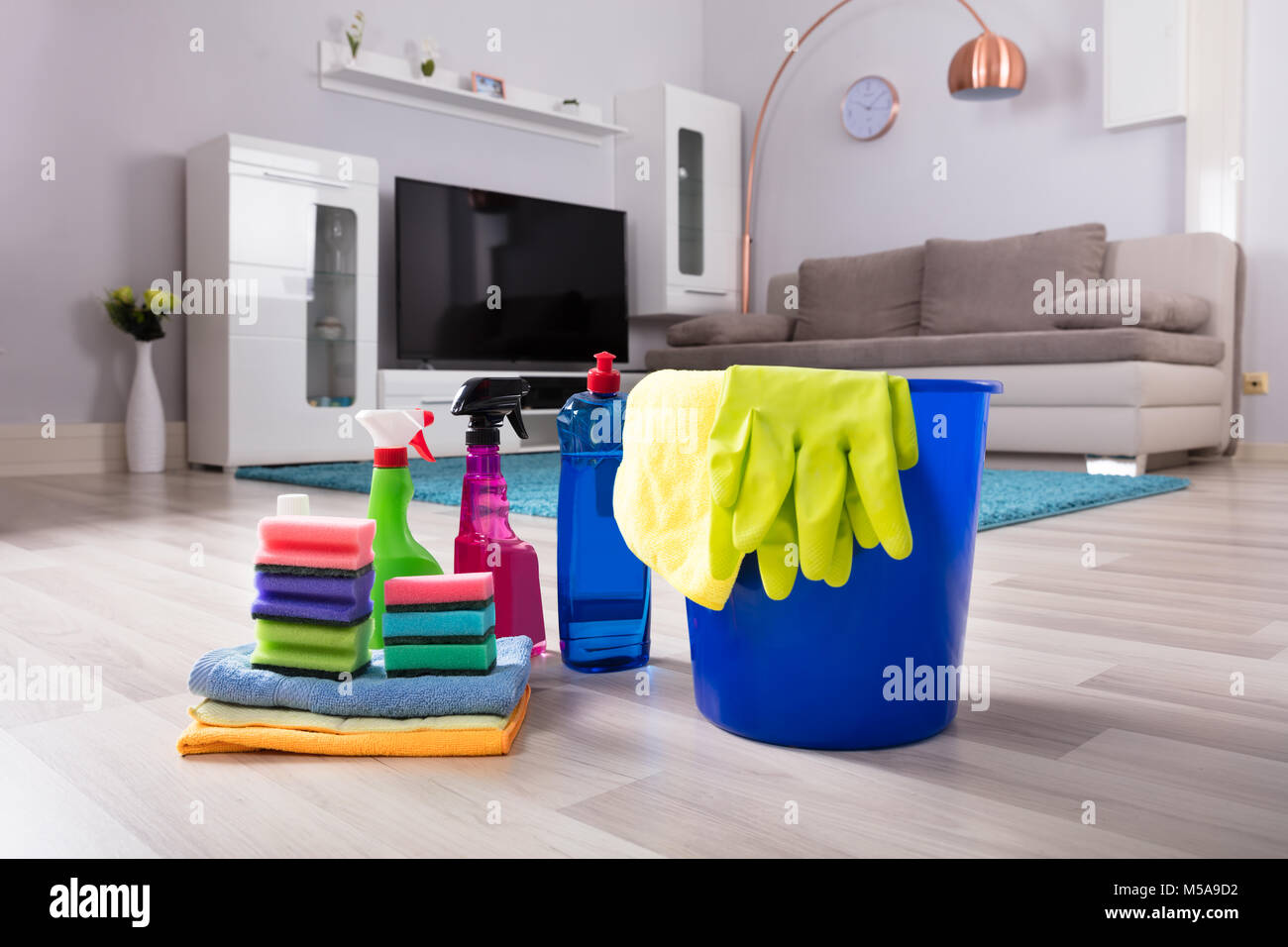 Blue Colored Bucket With House Cleaning Products On Hardwood Floor At Home Stock Photo