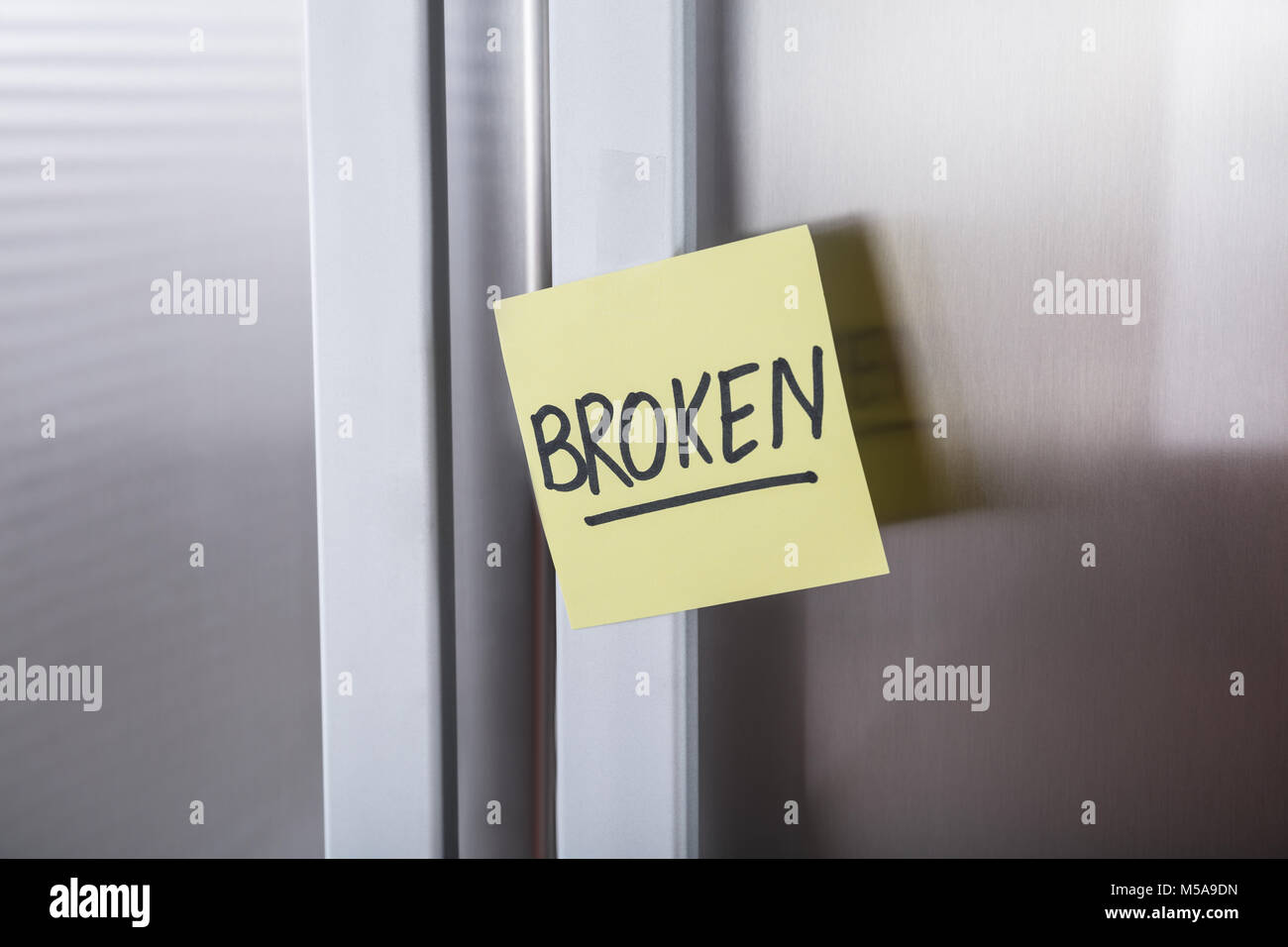 Close-up Of A Steel Refrigerator With Adhesive Notes Showing Broken Text Stock Photo