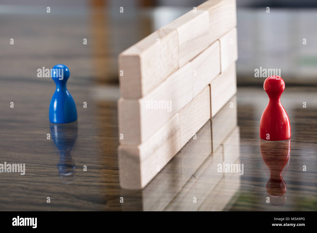 Close-up Of Red And Blue Figurine Paw Separated By Wooden Blocks On Desk Stock Photo