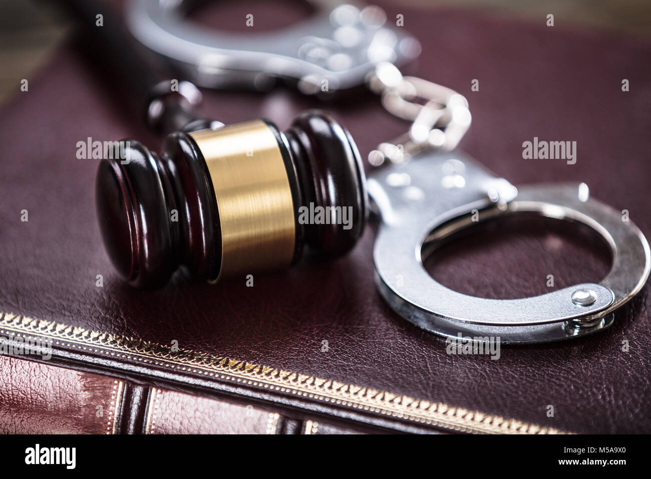 Close-up Of Handcuffs And Gavel On Law Book In Courtroom Stock Photo