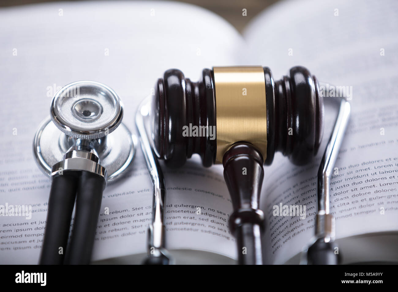Close-up Of Stethoscope And Gavel On Open Law Book Stock Photo