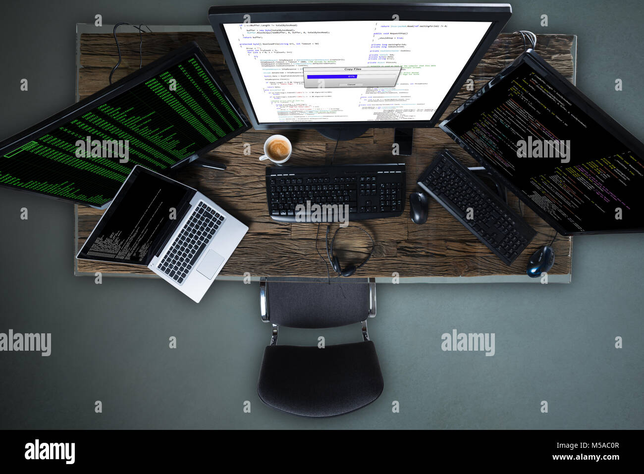 High Angle View Of Multiple Computer Screen Showing Progress Bar Of Copying File On Desk Stock Photo