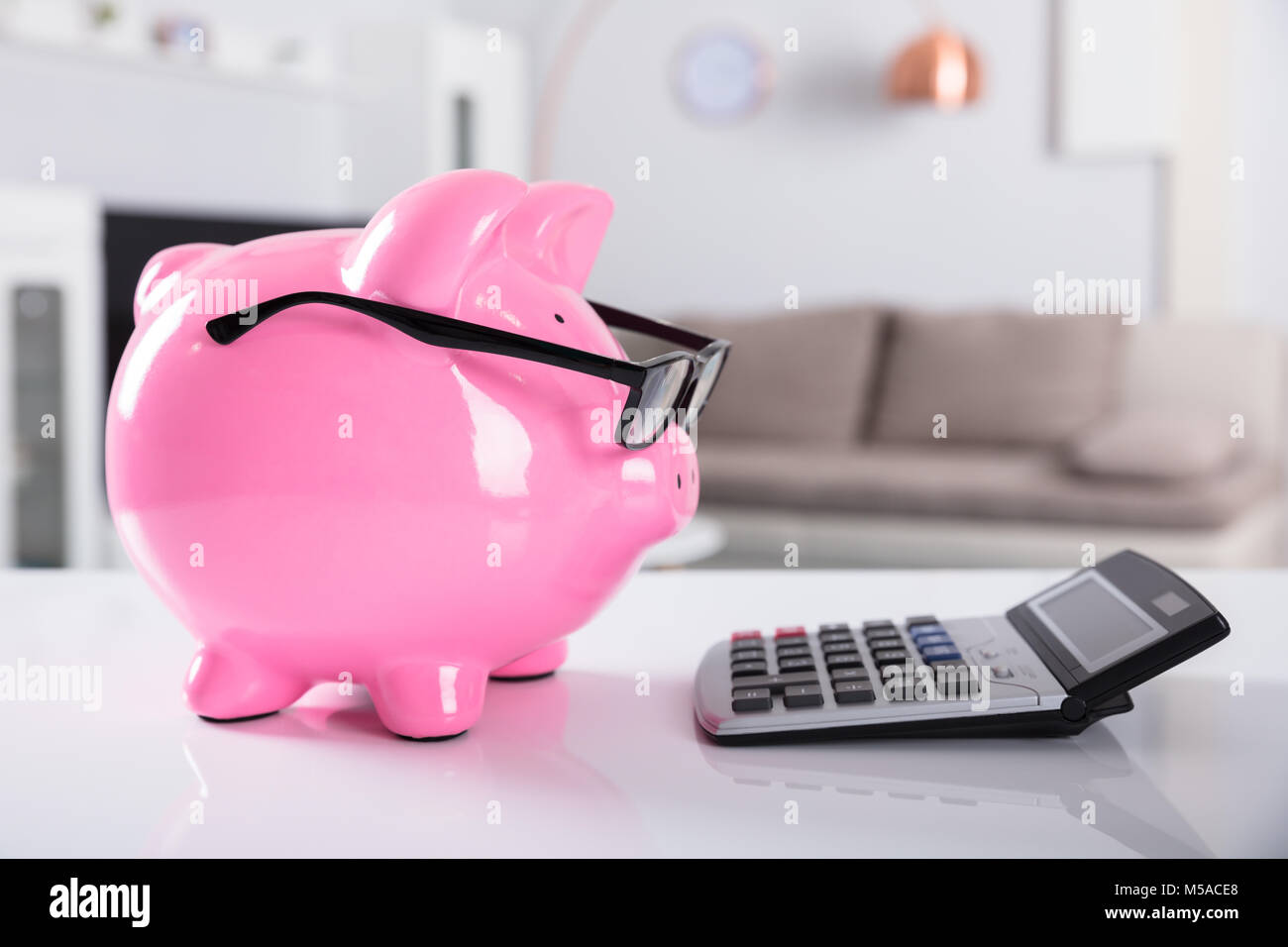 Close-up Of Pink Piggybank Wearing Spectacles With Calculator On Desk ...