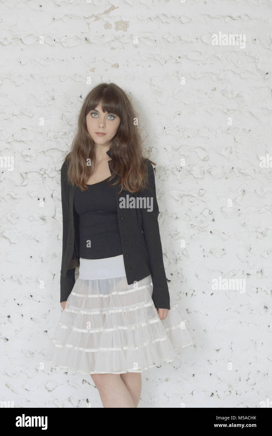 A beautiful girl with long brown hair dances in front of a white ...