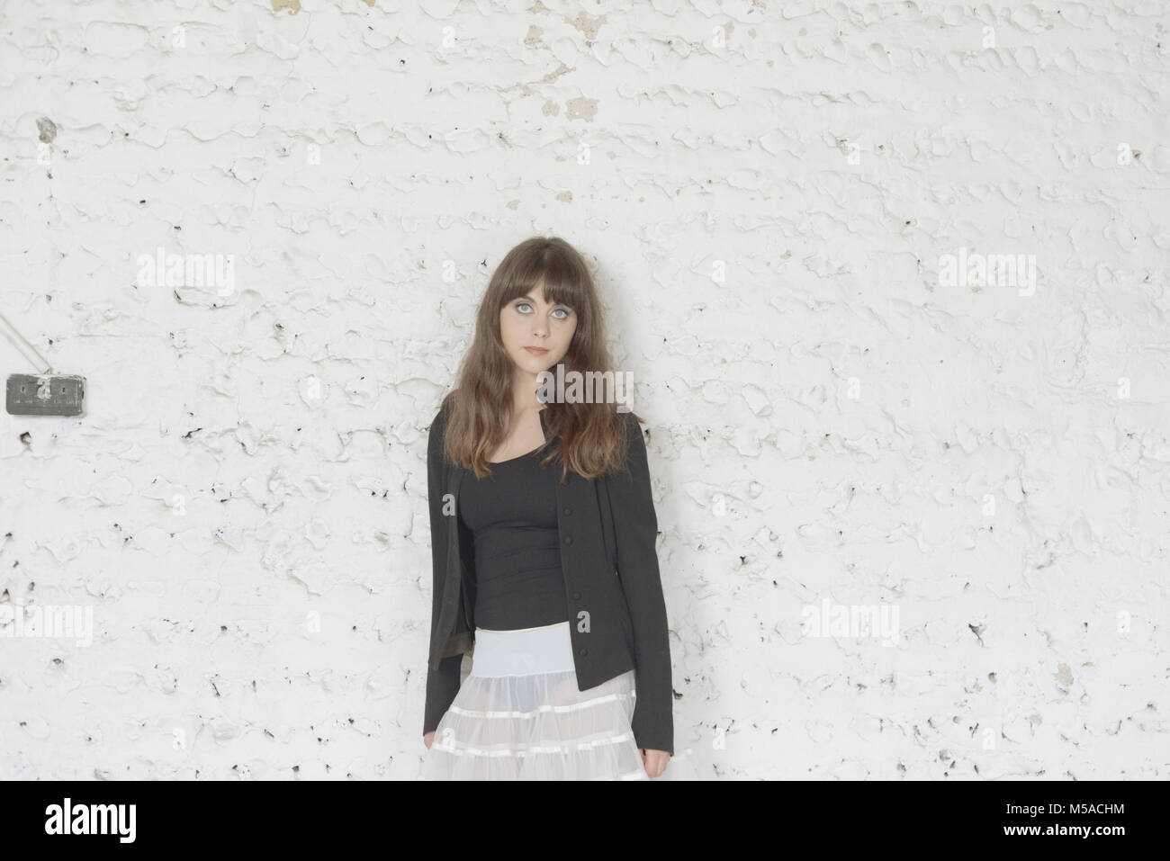 A beautiful girl with long brown hair dances in front of a white ...