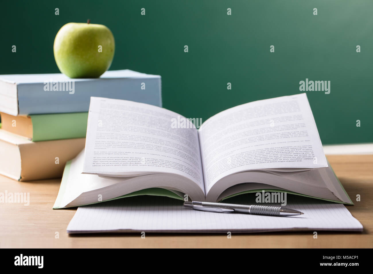 Close-up Of School Textbook On Desk In Front Of Blackboard Stock Photo